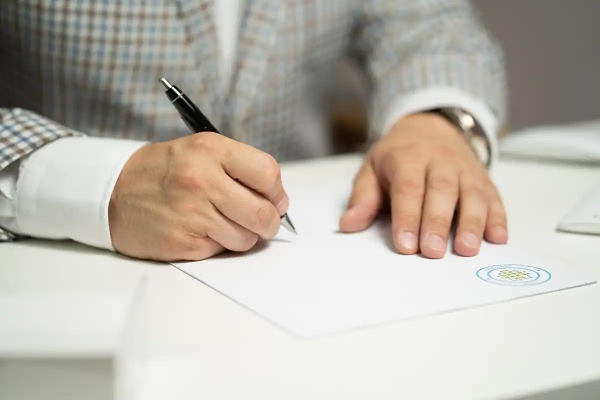 Bărbat la birou care semnează un document cu ștampilă pentru donația unui imobil