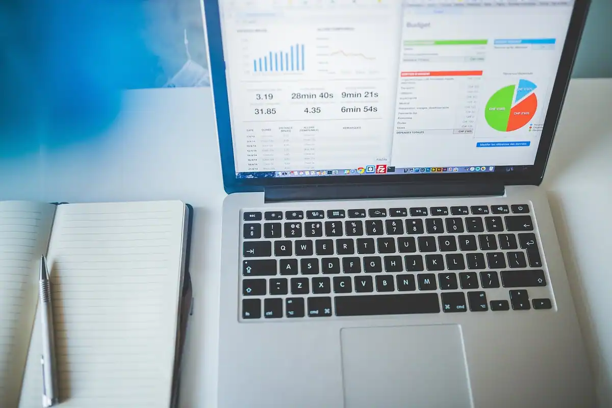 Laptop cu grafice financiare și carnet cu pix pentru calculul impozitului pe moștenire