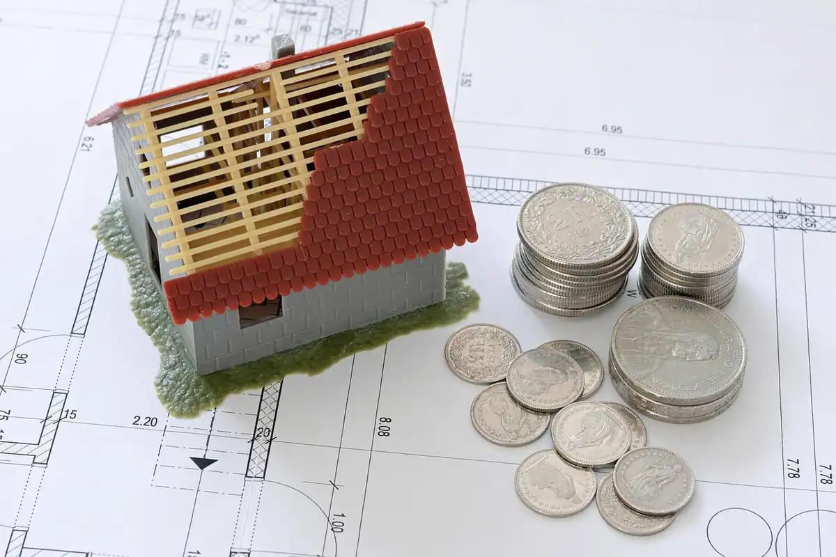 Machetă de casă și monede pe planuri, simbol al costurilor unei moșteniri