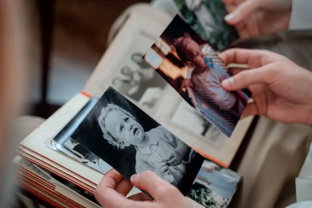 Mâini care răsfoiesc un album cu fotografii vechi de familie