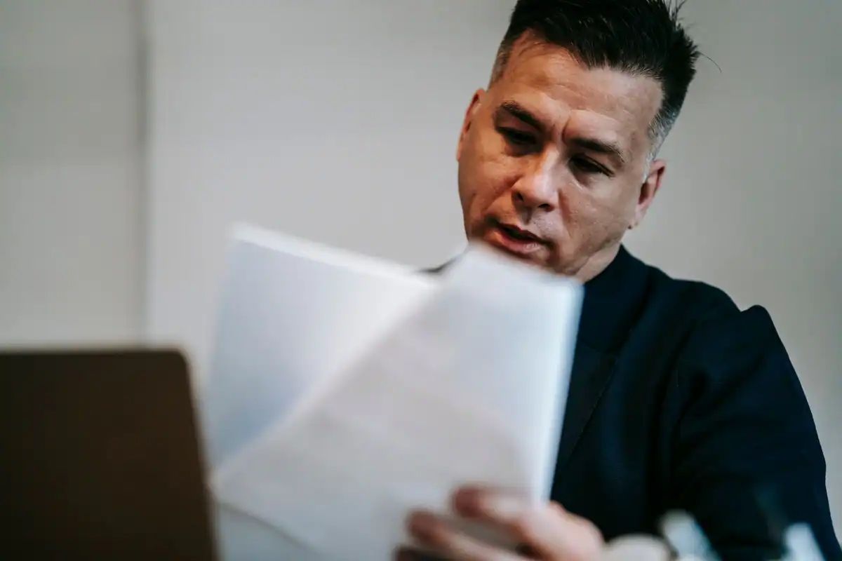 Bărbat concentrat care citește o hârtie la biroul său