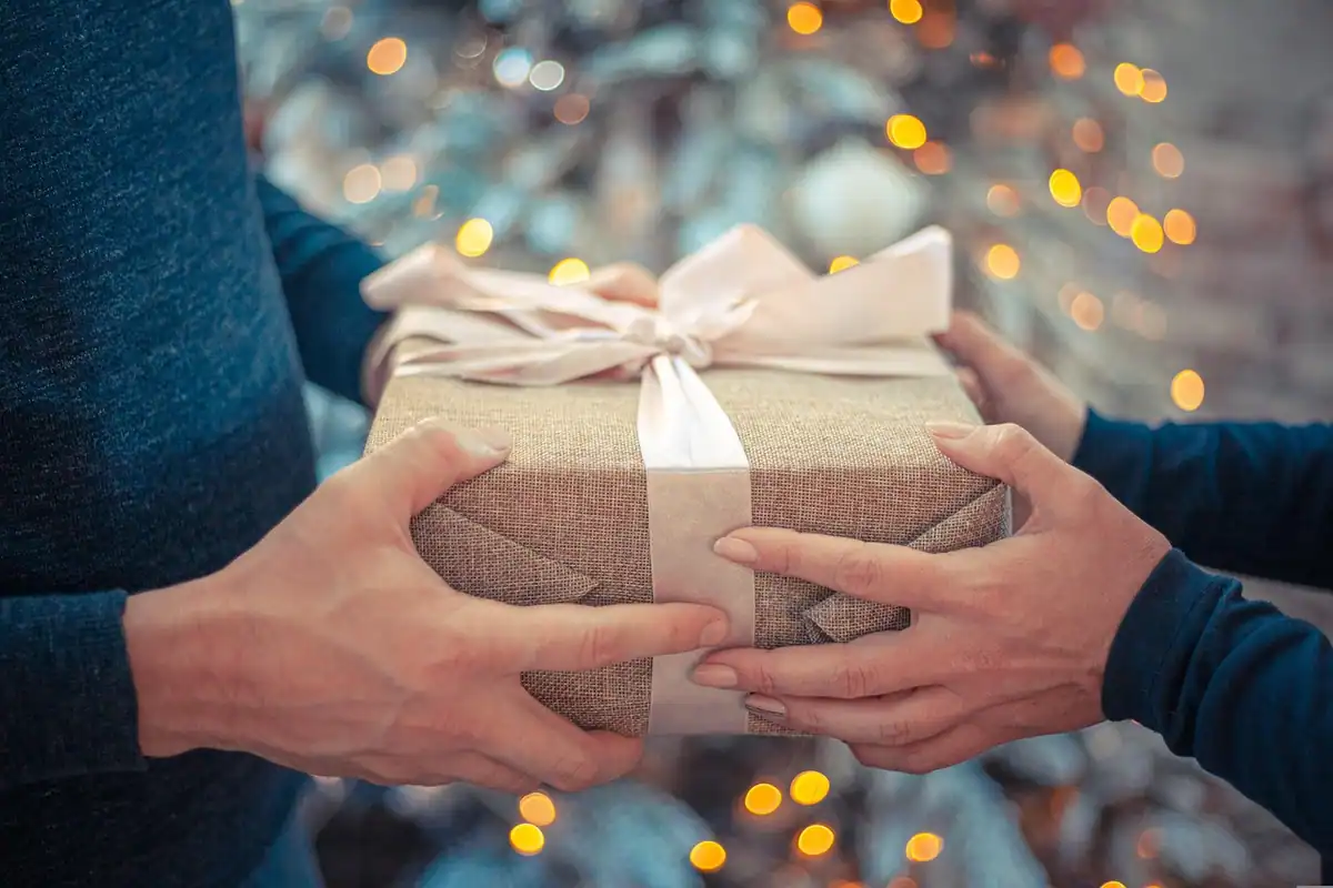 Mâini care își dau un cadou ambalat, simbol al donațiilor din familie