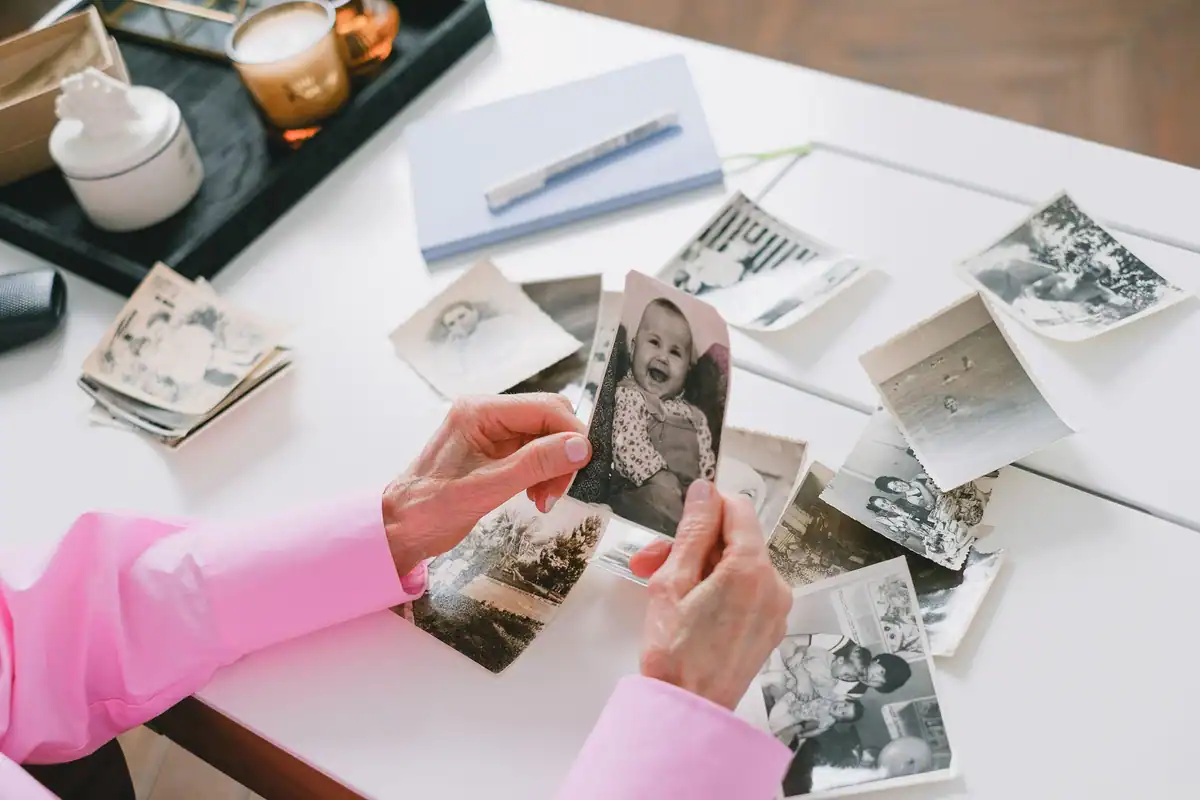 Femeie care sortează fotografii vechi alb-negru ale familiei pe o masă